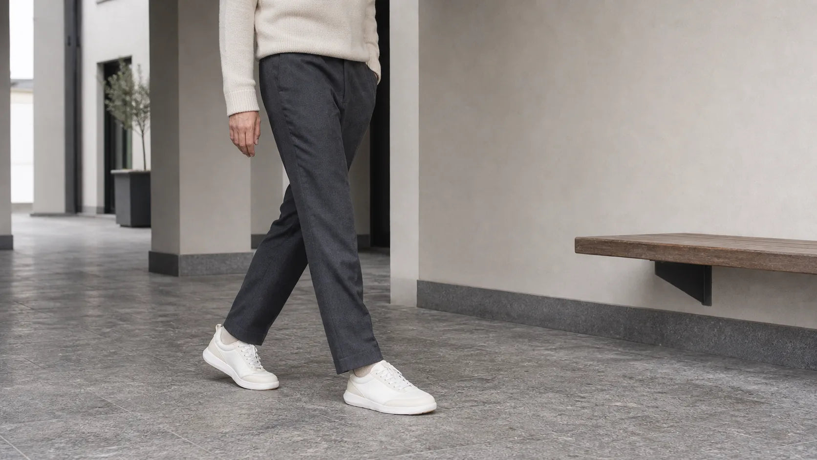 A person wearing white Footle sneakers while walking through the city