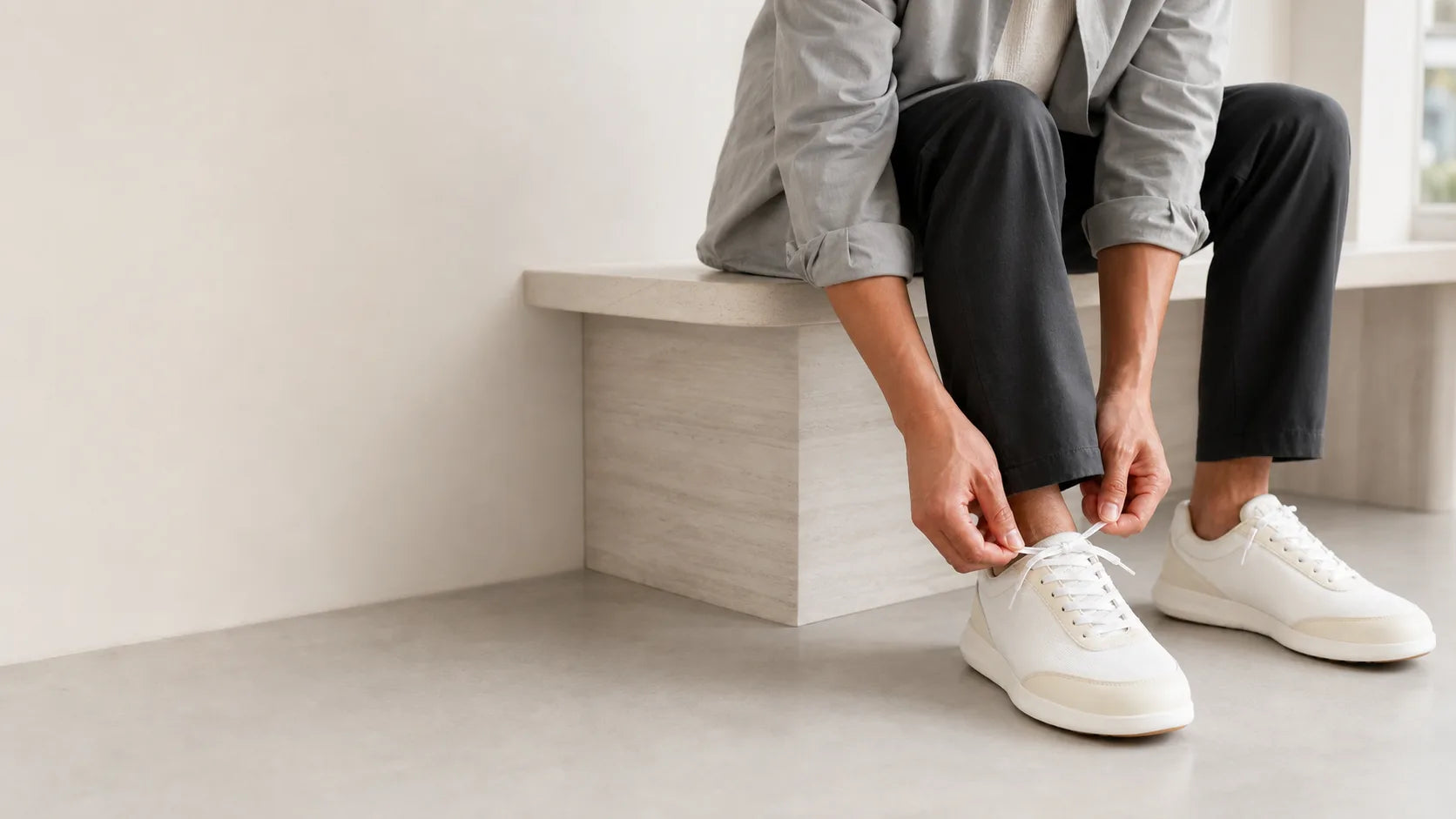 A person tying white Footle sneakers at the start of the day